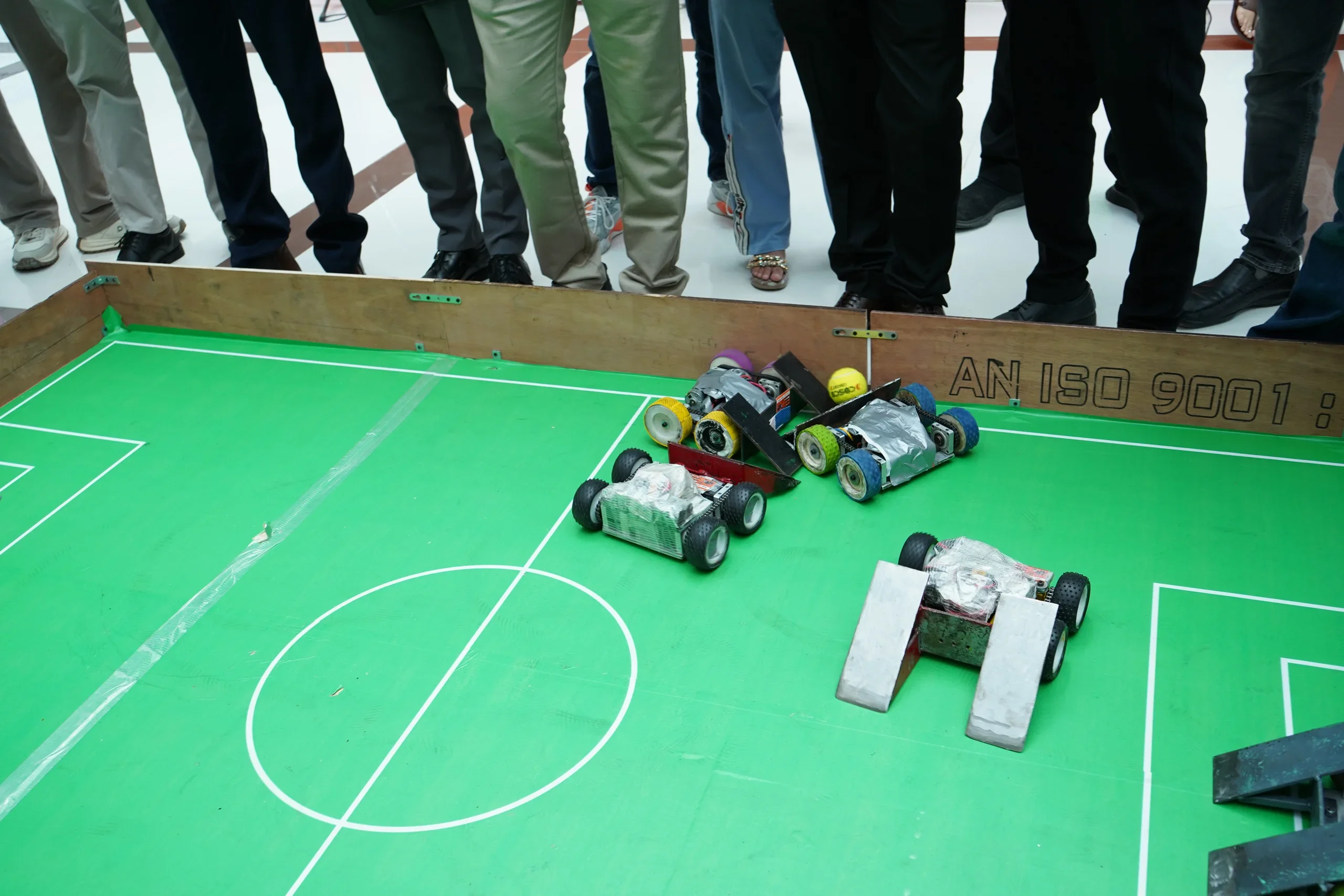 Student-built soccer robots contesting possession on the green RGI pitch